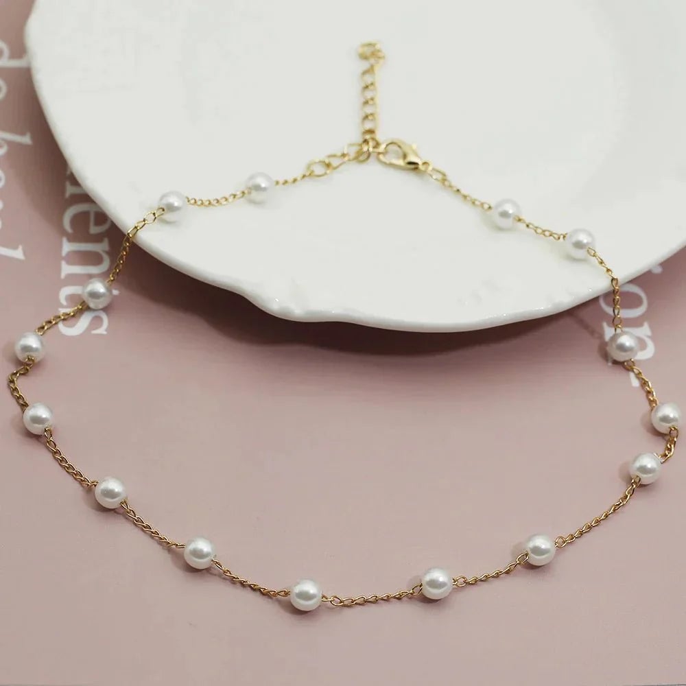 Gold pearl necklace styled flat lay showing warm gold-tone hardware and pearl accent
