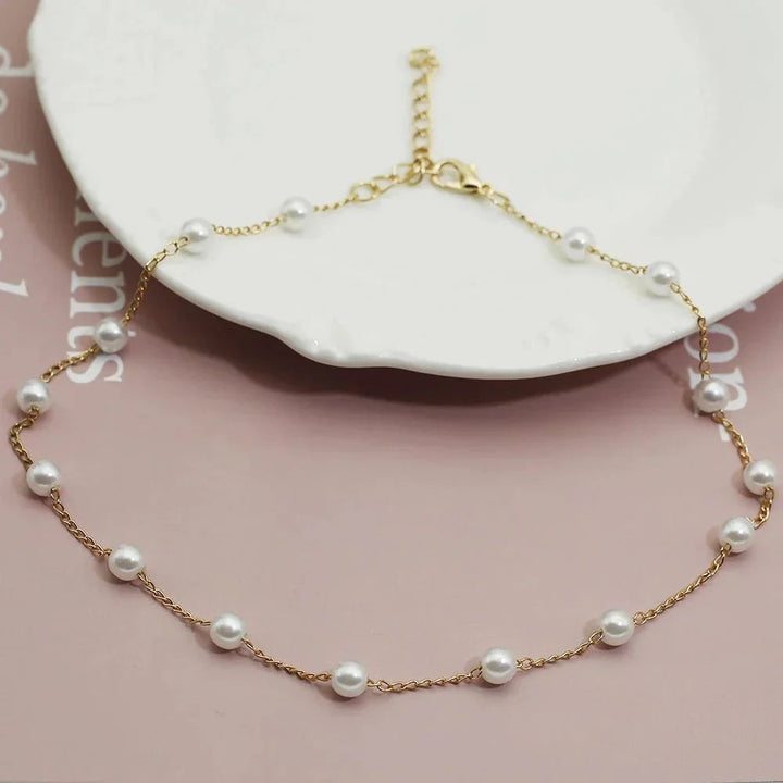 Gold pearl necklace styled flat lay showing warm gold-tone hardware and pearl accent