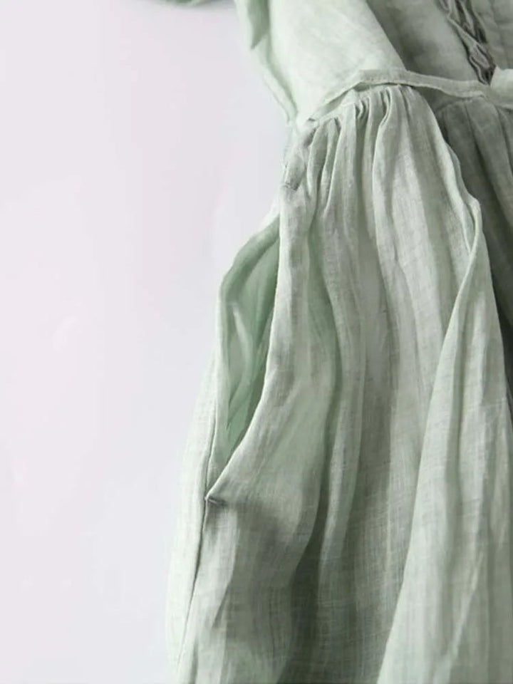 Woman styled in the Madeleine vintage-inspired dress in green paired with strappy sandals for a garden party look