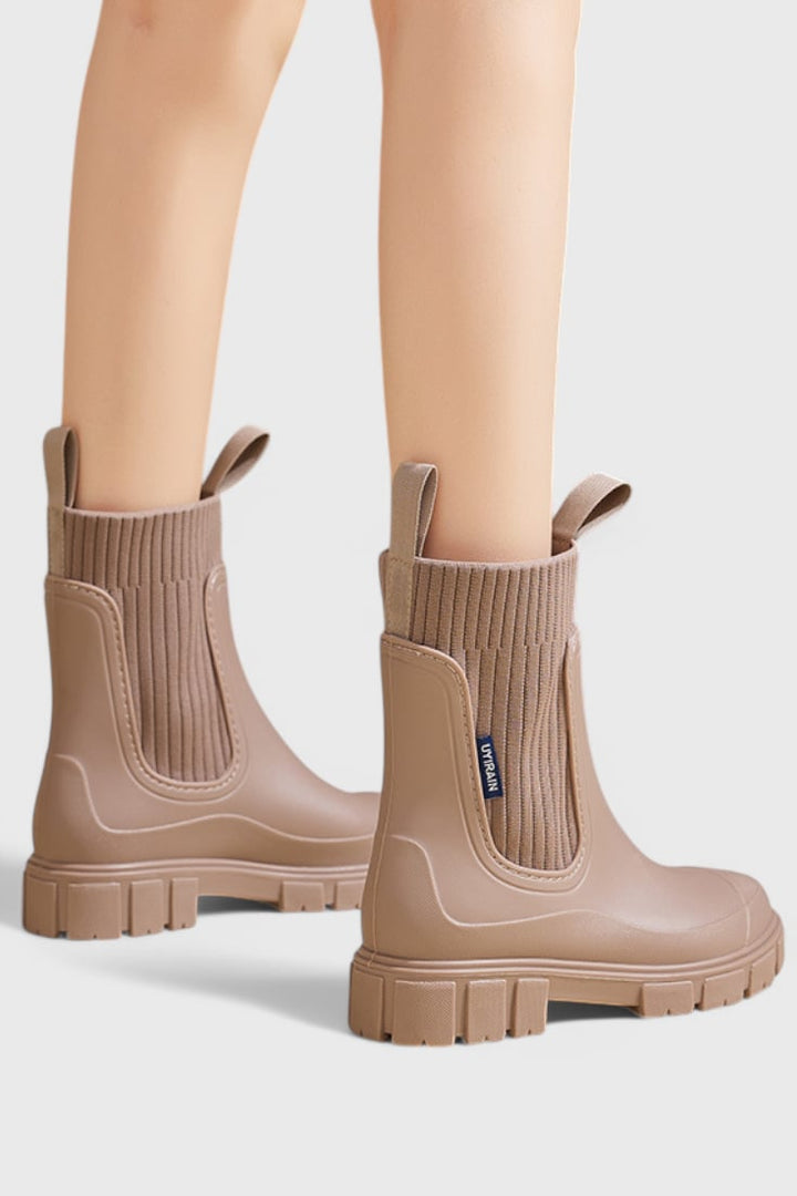 Maelie Chelsea boots on model walking on wet pavement, showcasing waterproof protection