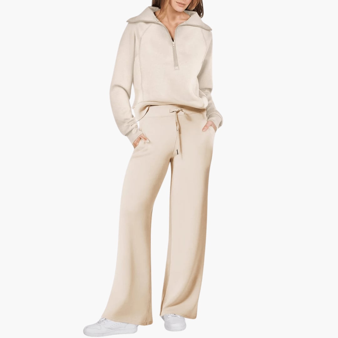 Woman wearing a beige zip-up hoodie and wide leg lounge pants set, standing in a relaxed pose