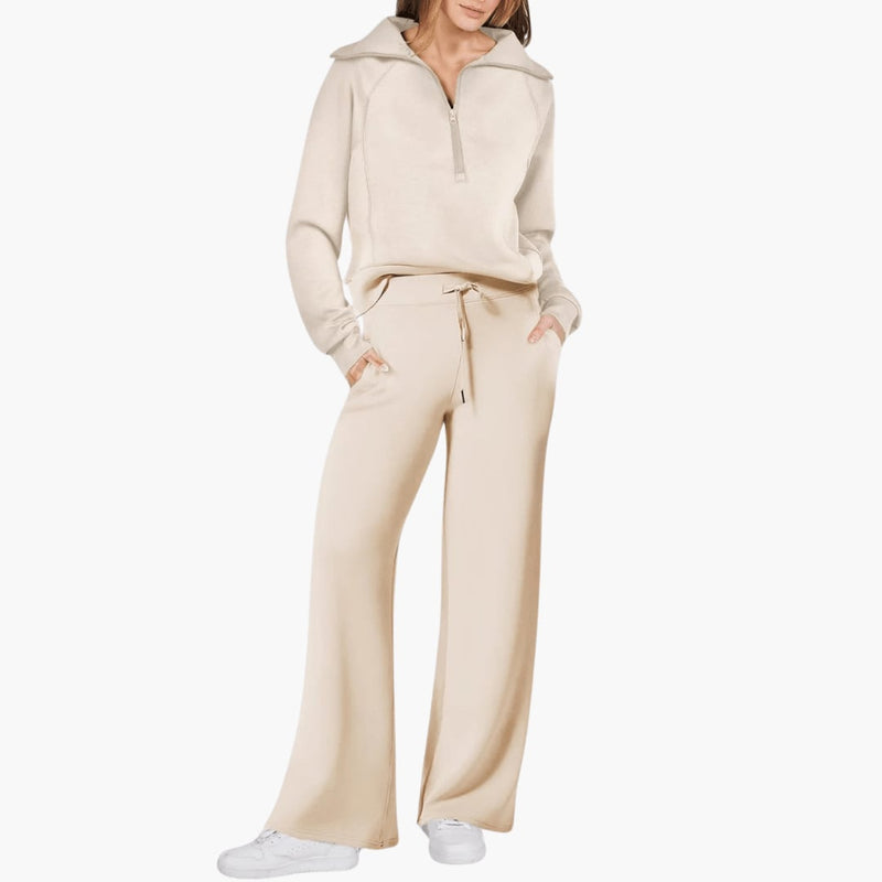 Woman wearing a beige zip-up hoodie and wide leg lounge pants set, standing in a relaxed pose