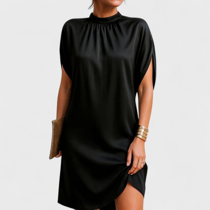Woman wearing a black mock neck split sleeve mini dress with a gathered neckline and side slit hem, front view