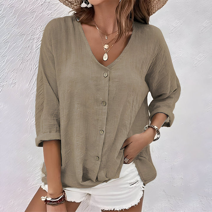 Flat lay of a relaxed women's button-up blouse showing fabric texture and button front