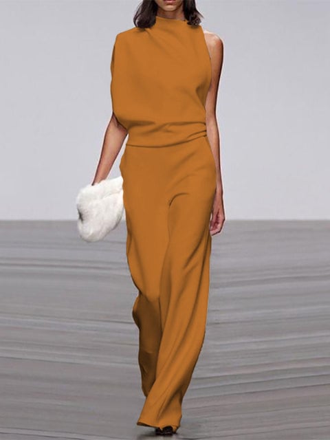 Woman in a blue one-shoulder sleeveless wide-leg jumpsuit, side silhouette view