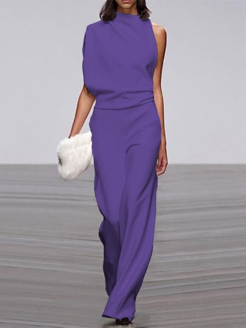 Close-up of the white jumpsuit's asymmetric neckline and shoulder drape detail