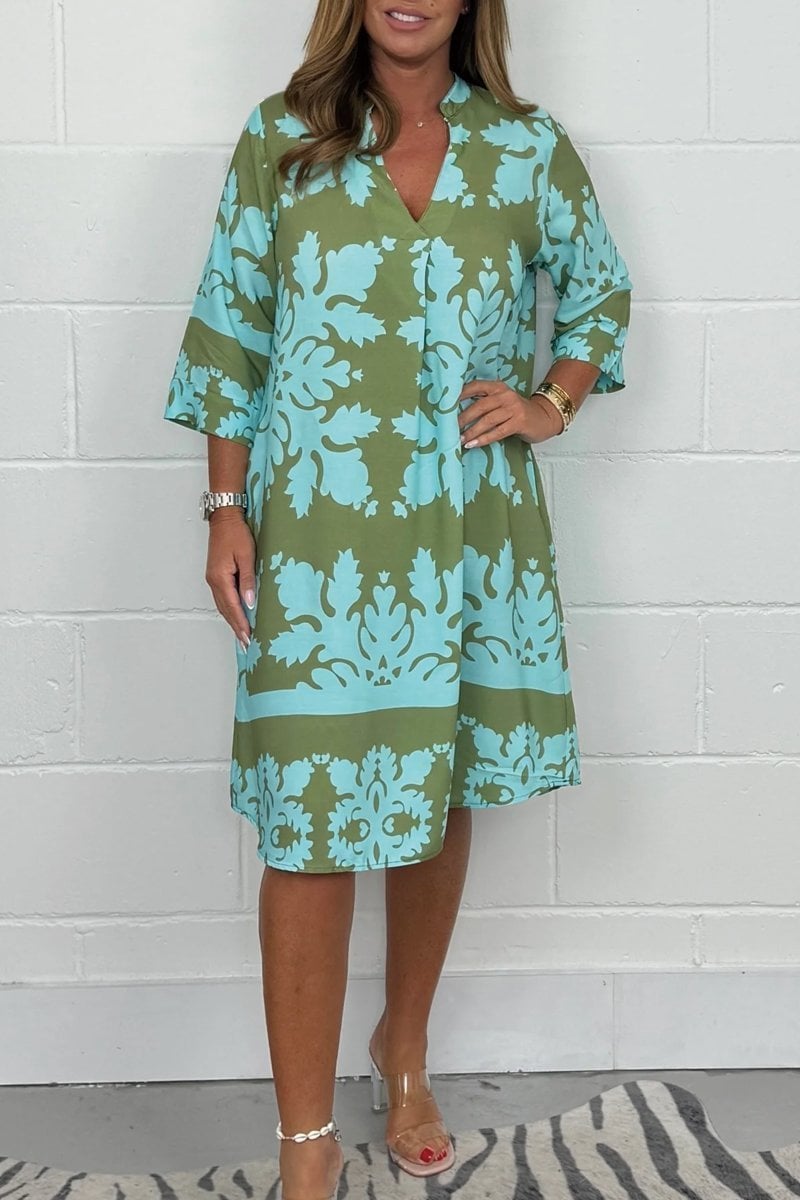 Woman wearing the Margaret light summer dress in green with a soft V-neckline and flowing silhouette, styled for a casual summer day