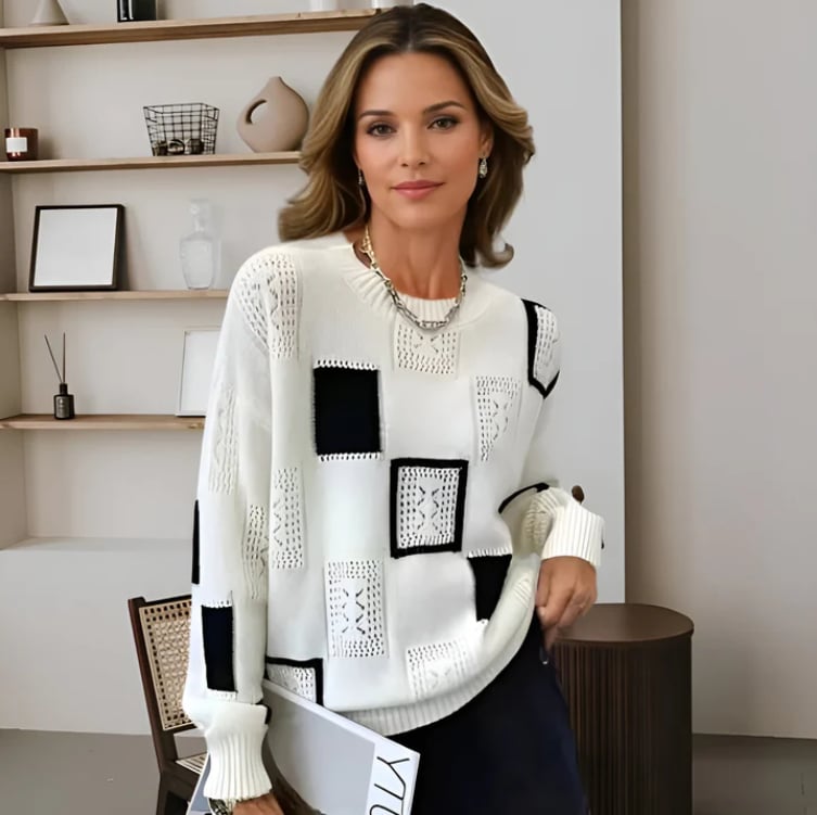 Woman wearing a black patchwork sweater with ribbed detailing, styled with jeans for a casual winter look