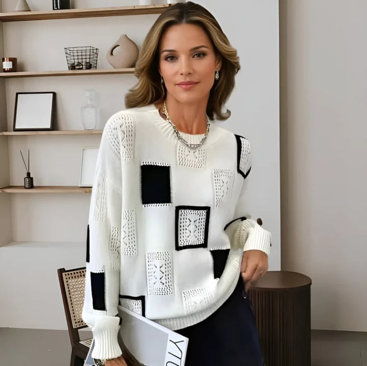 Woman wearing a black patchwork sweater with ribbed detailing, styled with jeans for a casual winter look