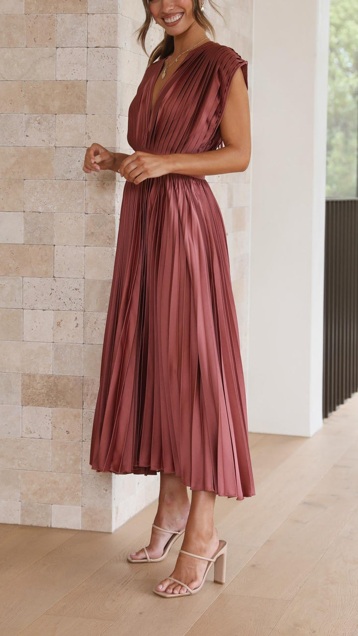 Back view of model in antique pink pleated maxi dress with draped neckline detail