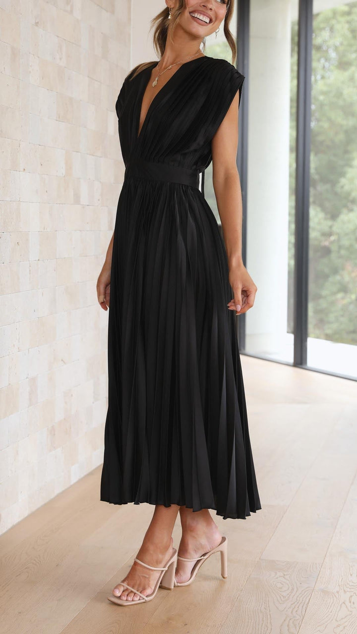 Model wearing elegant pleated maxi dress in grey with draped neckline and flowing pleated skirt