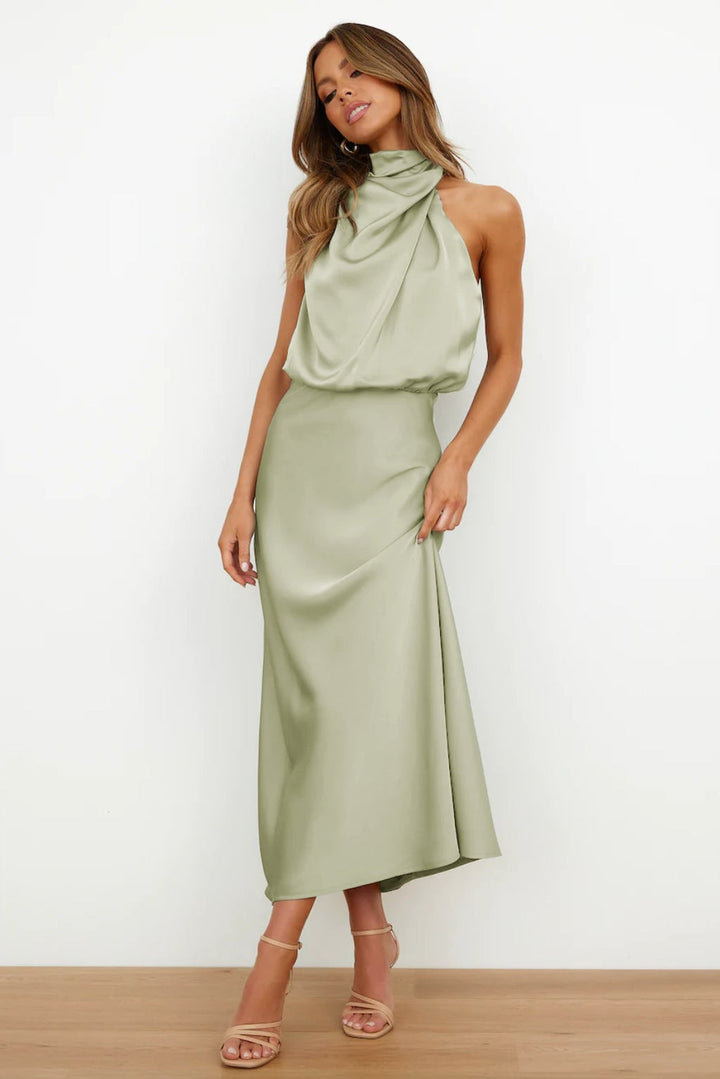 Close-up of the satin fabric and flowing skirt of the Mariana halter evening dress in light green