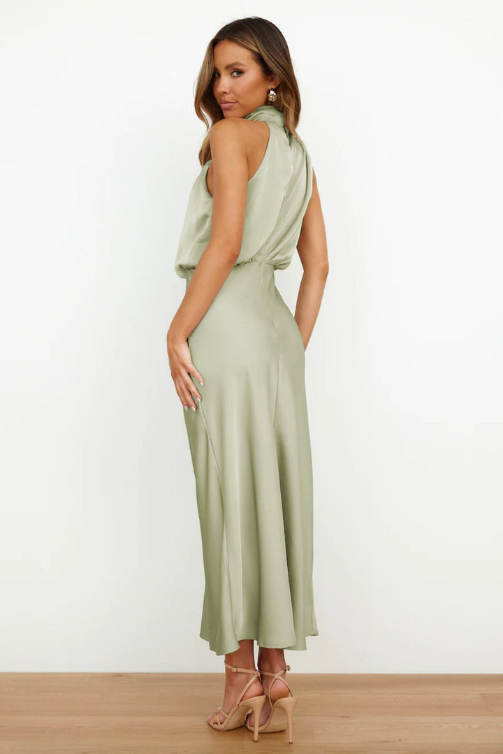Model wearing a beige satin halter evening dress with an elegant elongated silhouette