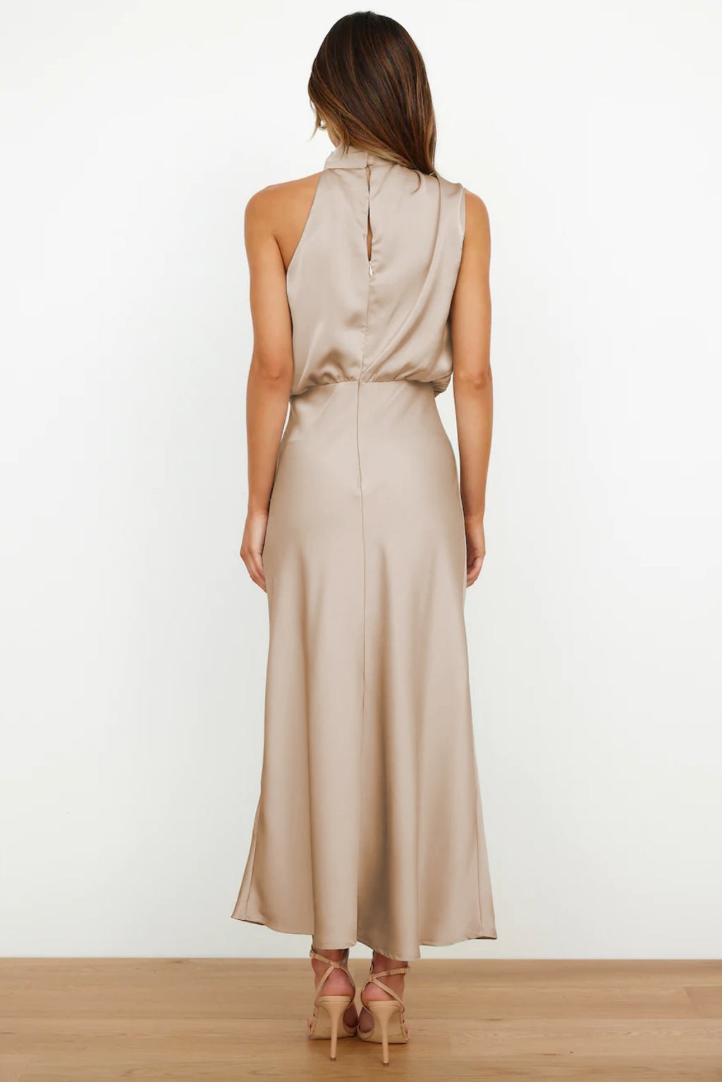 Model in an olive green halter evening dress with a sleek satin finish and flowing skirt