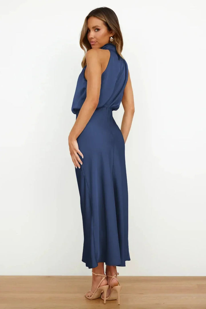 Full-length shot of a model in a light green halter evening dress at a formal setting