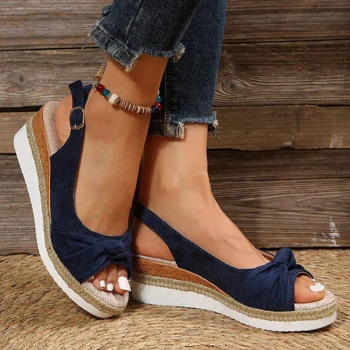 Marinette sandals in beige worn on feet against a bright summer background
