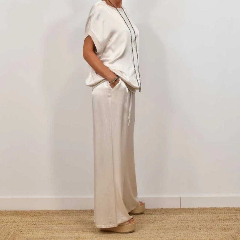 Flat lay of the Marla blouse and pants set in white on a light background