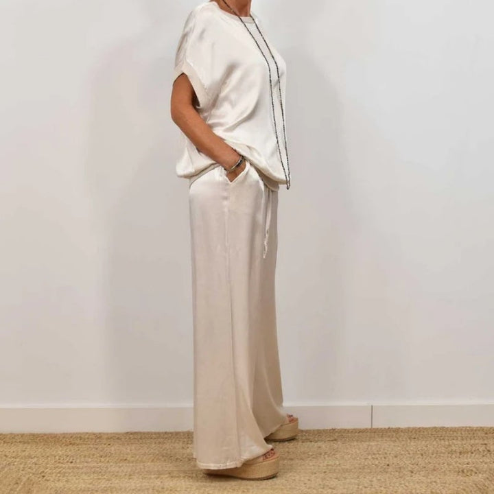 Flat lay of the Marla blouse and pants set in white on a light background