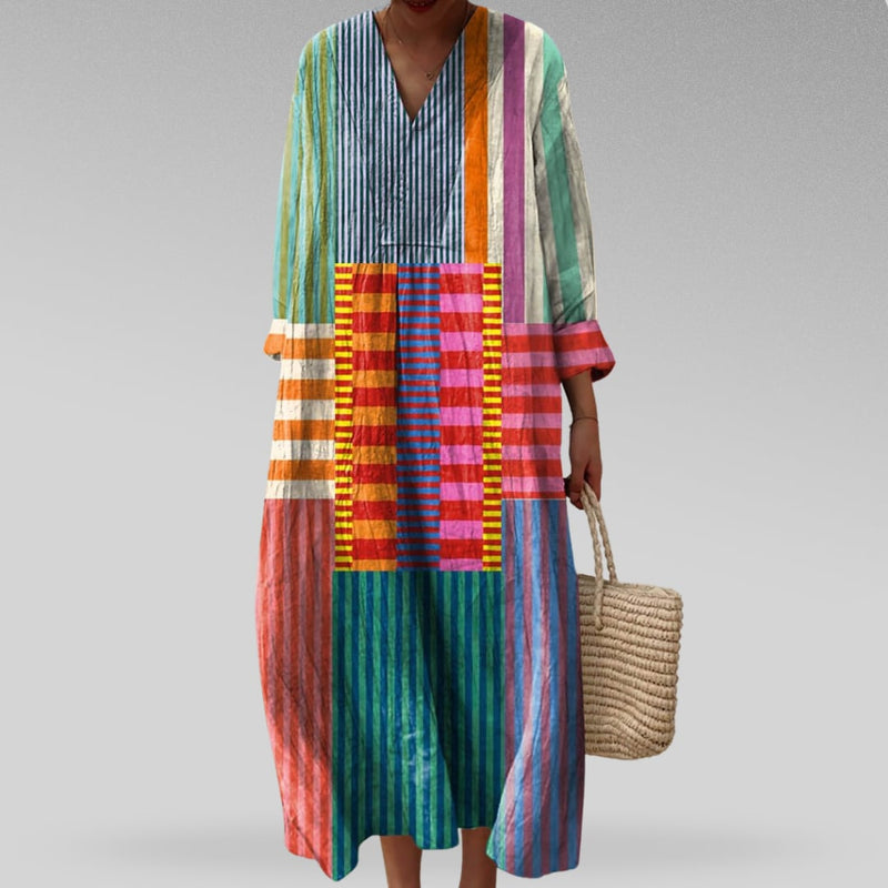 Model wearing a flowing geometric print dress with a Dreamtime-inspired pattern in relaxed silhouette, shown in a studio setting