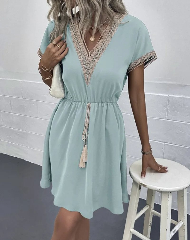 Close-up of the V-neckline and waist tie detail on a white boho draped dress