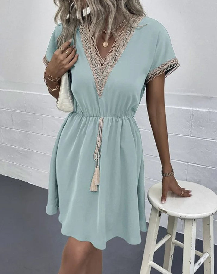 Close-up of the V-neckline and waist tie detail on a white boho draped dress