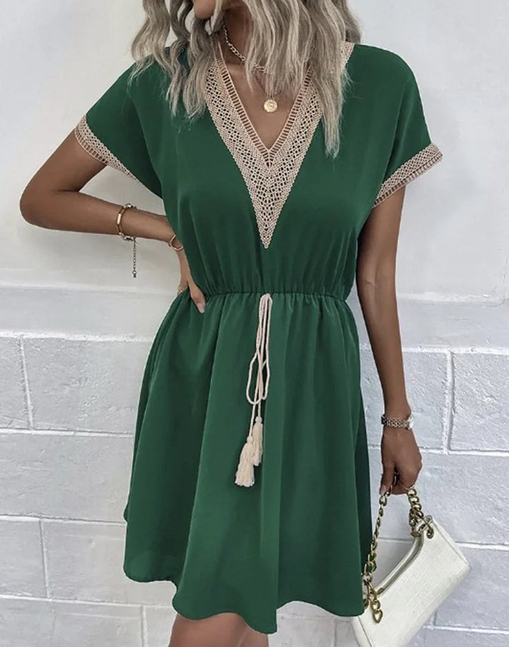 Back view of a woman wearing a black boho V-neck draped dress with a tied waist