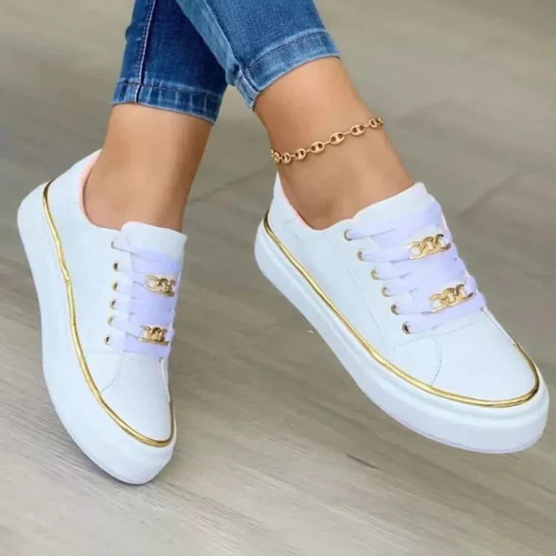 Side view of black lace-up platform sneakers with decorative gold chain accent and metallic gold sole edge