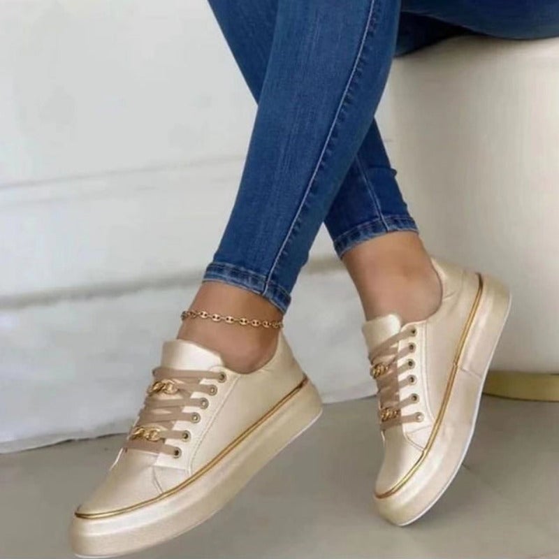 Close-up of gold chain hardware detail on the tongue of black women's platform sneakers