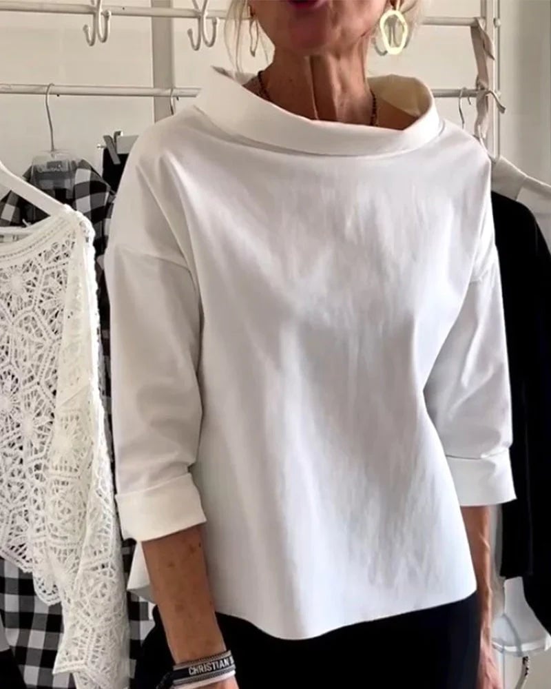 Woman wearing a white relaxed drop-shoulder bateau neck top with 3/4 cuffed sleeves, front view