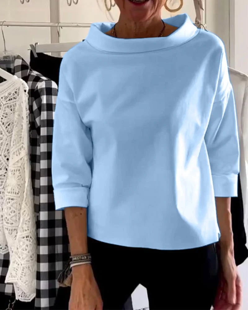 Close-up of the draped cowl neckline detail on a white women's casual top