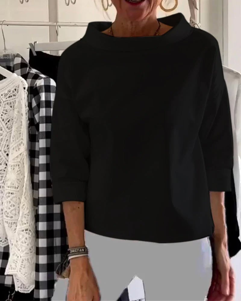 Woman in a white bateau neck top paired with dark jeans, side profile view