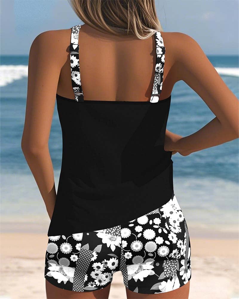 Model laughing on the beach wearing the black floral two-piece tankini swimsuit set