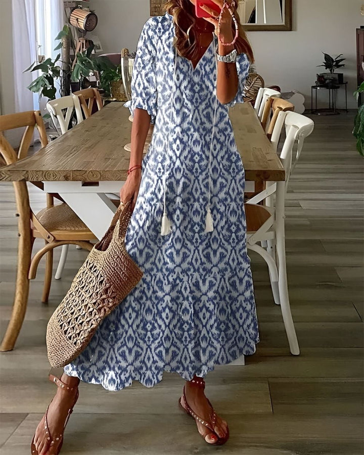 Woman wearing a flowy blue boho covering dress with tassel details on a sunny day