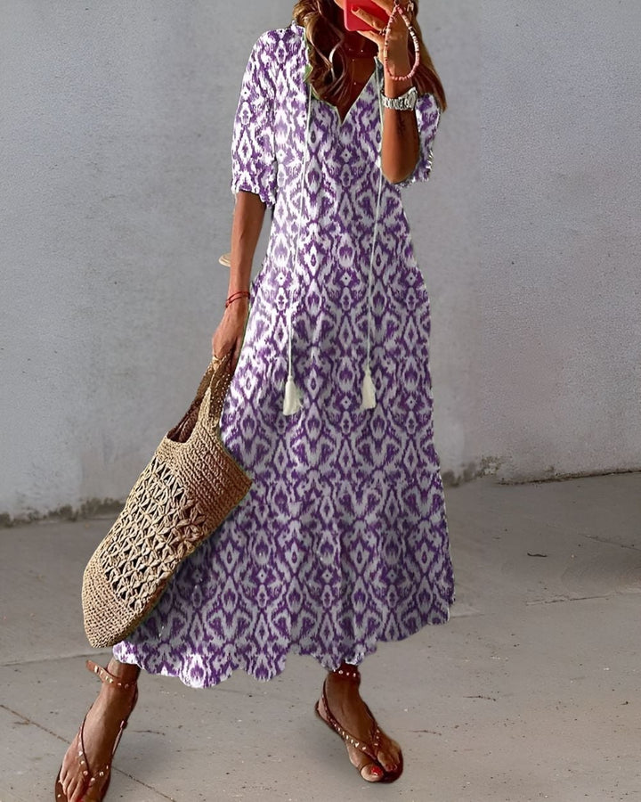 Woman in a flowing green boho dress with playful pattern details and tassel accents
