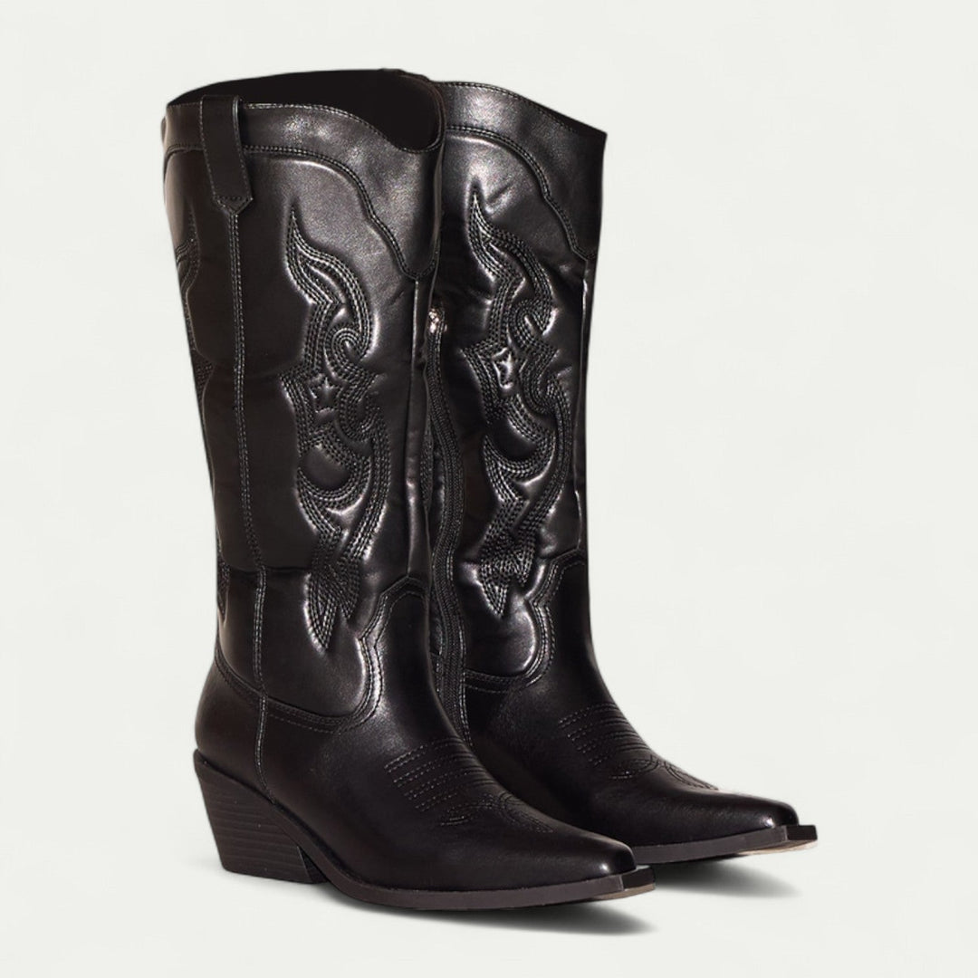 Woman wearing black calf-high western pointed toe boots styled with slim jeans