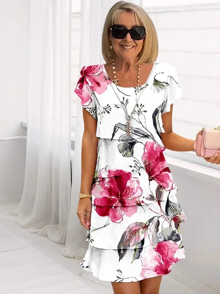 Woman wearing a white ruffled floral pleated dress with cascading layers and playful ruffle detailing