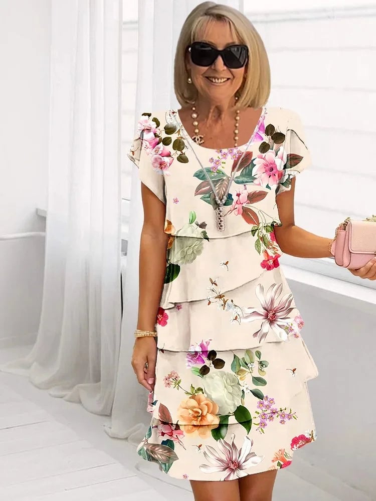 Full-length view of a woman in a purple floral pleated dress with flowing ruffled skirt