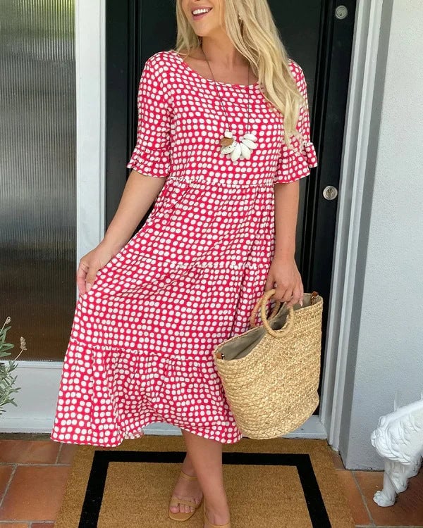 Model wearing a relaxed tiered midi dress with a scattered dot print in black, styled with sandals