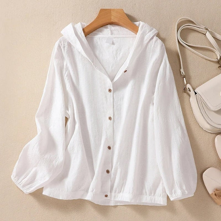 Woman wearing a relaxed white hooded shirt with clean cuffs and a softly draped silhouette