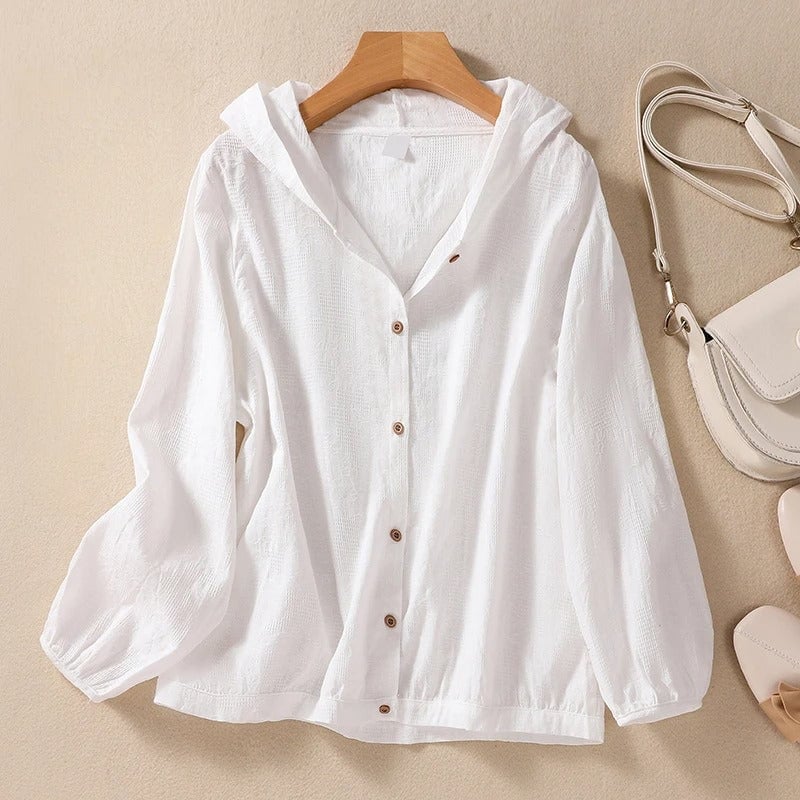 Woman wearing a relaxed white hooded shirt with clean cuffs and a softly draped silhouette