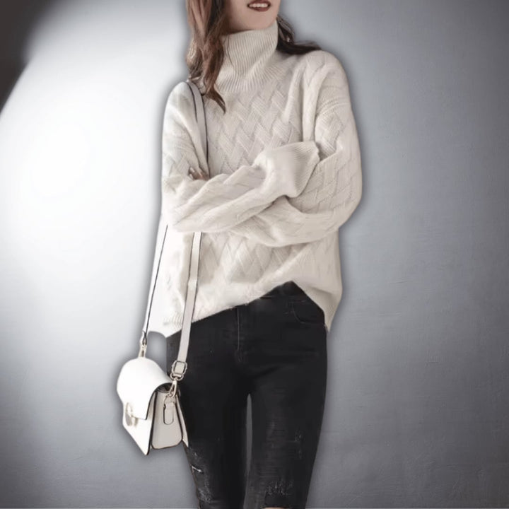 Detail shot of the neckline and sleeve of a soft oversized sweater in light beige