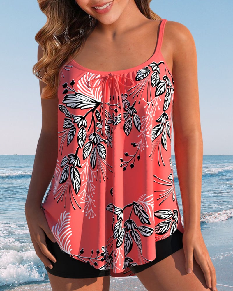 Woman wearing a red tropical-print tankini with adjustable spaghetti straps and high-waisted shorts at the beach