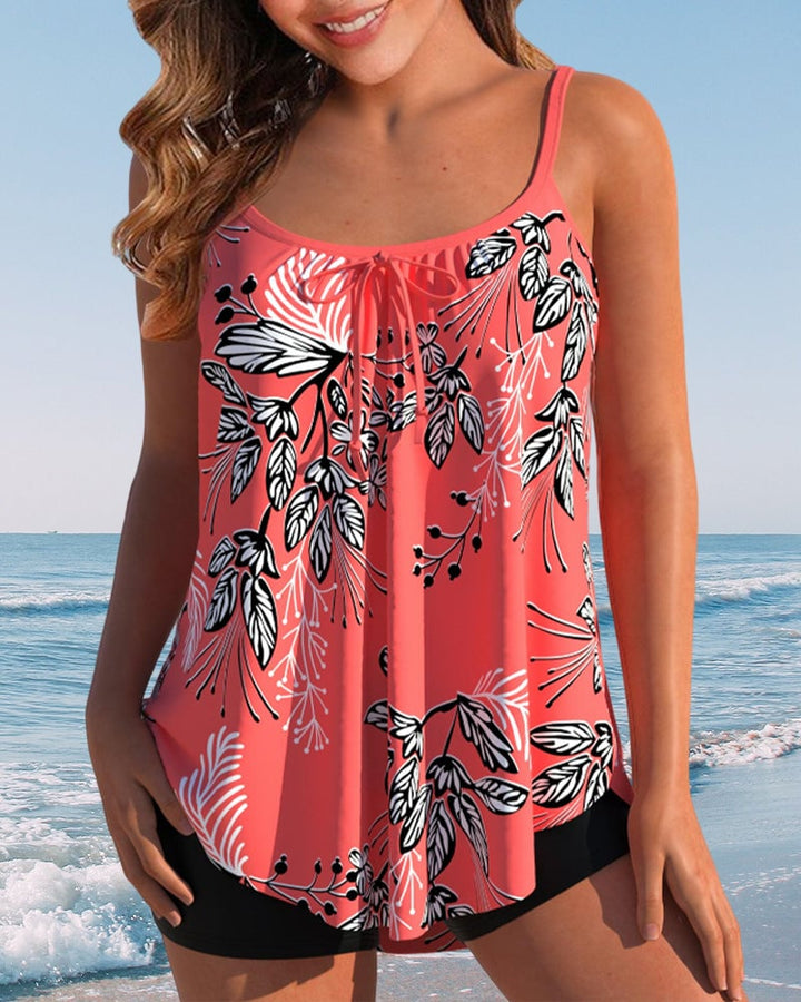 Woman wearing a red tropical-print tankini with adjustable spaghetti straps and high-waisted shorts at the beach