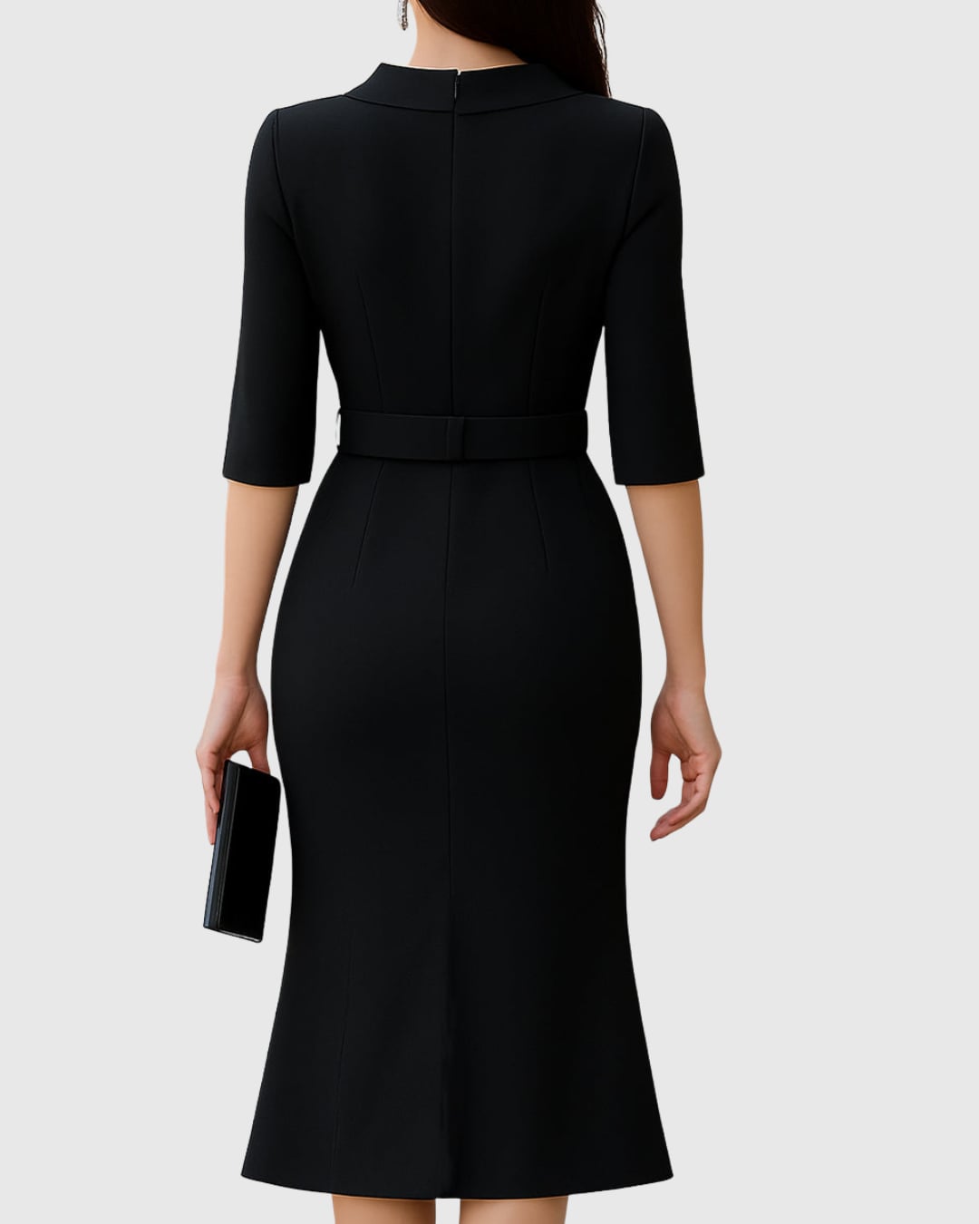 Close-up of the wide silver-buckle belt and folded mock neck collar on a black midi dress