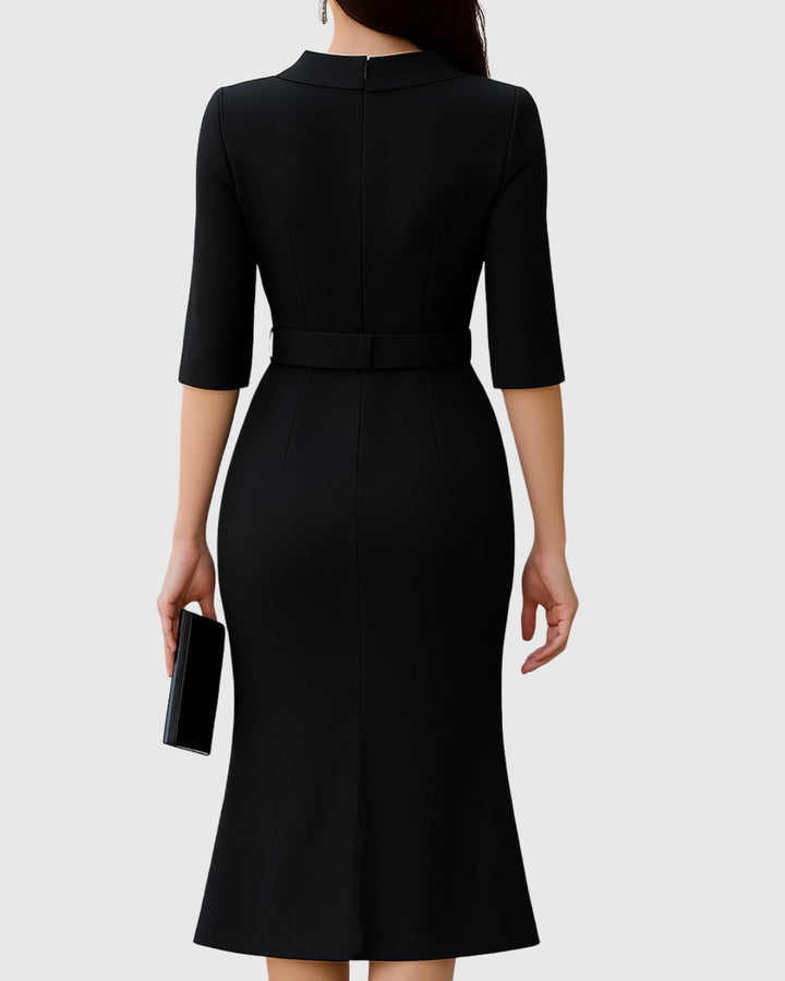 Close-up of the wide silver-buckle belt and folded mock neck collar on a black midi dress
