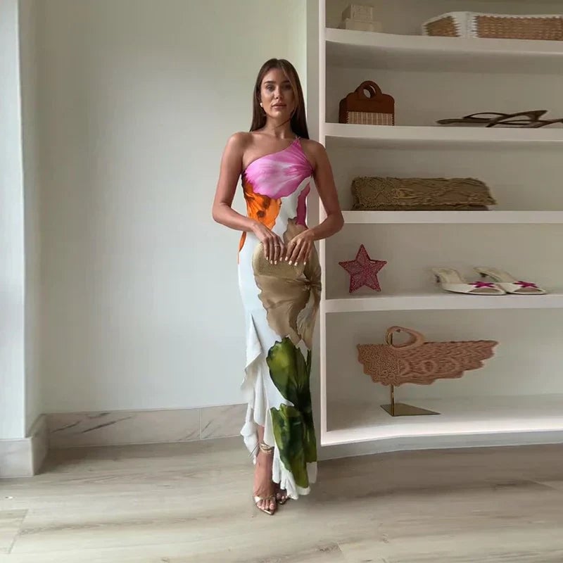 Woman wearing a white one shoulder floral maxi dress with a fitted silhouette and floor-sweeping hem
