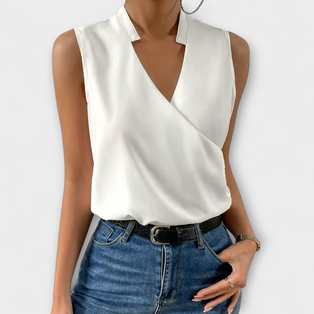 Woman wearing the Nina sleeveless wrap V-neck collared blouse in white, front view