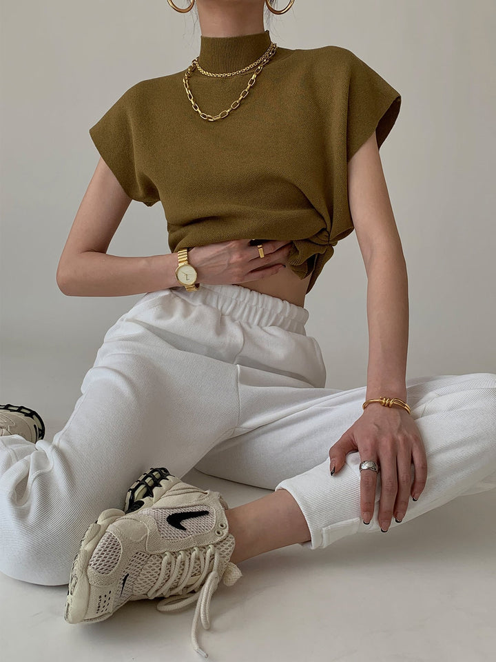 Model wearing the Noira sleeveless top in burgundy with dark trousers