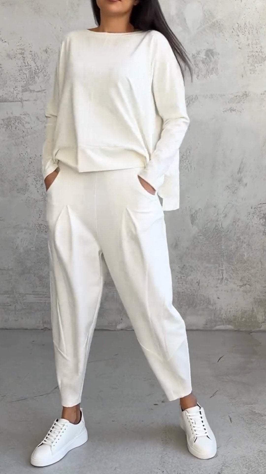 Woman wearing the Nora off-white 2-piece lounge set with boat-neck long-sleeve top and tapered pleated pants, front view