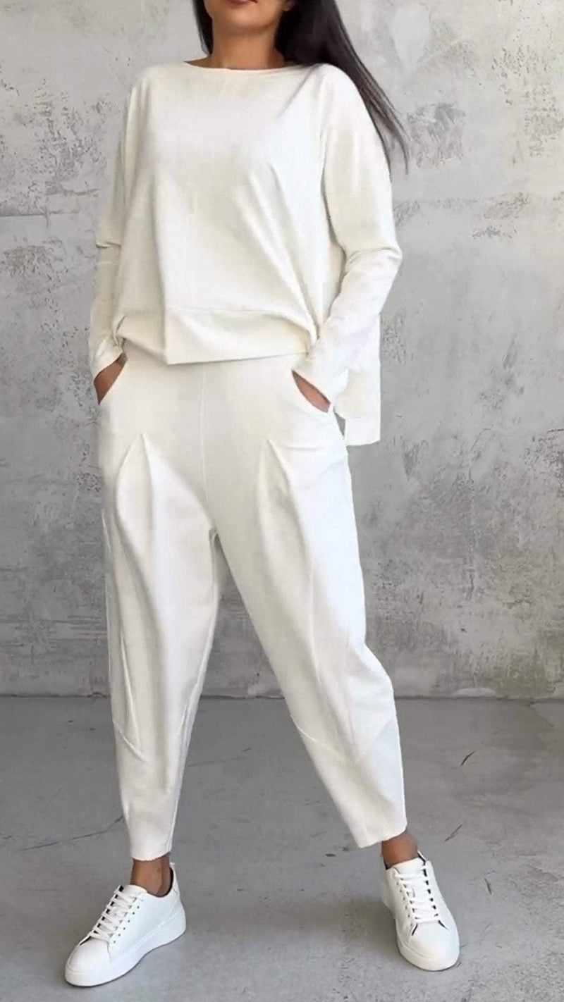 Woman wearing the Nora off-white 2-piece lounge set with boat-neck long-sleeve top and tapered pleated pants, front view
